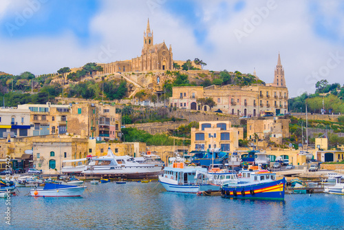 Cityscape view of Gozo island with medieval architecture and passenger boats on the harbour in Malta