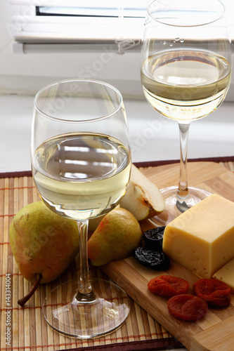 Glasses with white wine and cheese with fruit..