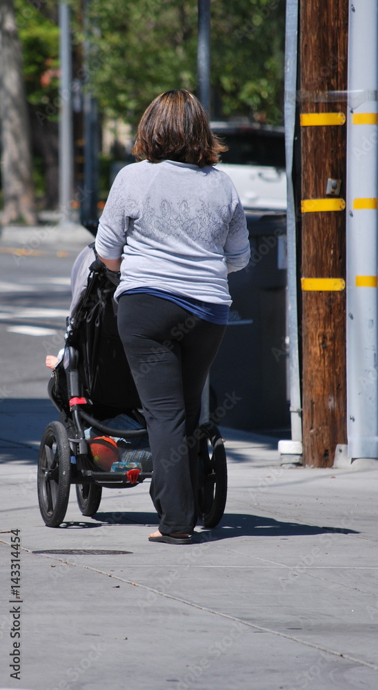 Mother walking with her newborn baby in stroller outside.