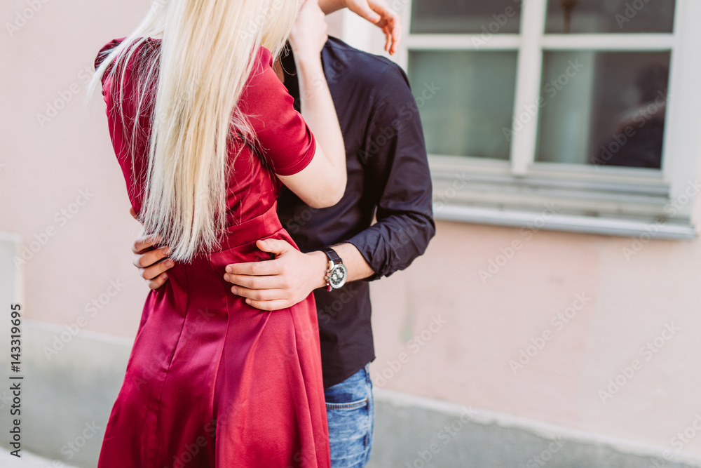 Verliebtes Paar umarmt sich in Altstadtgasse mit rotem Kleid