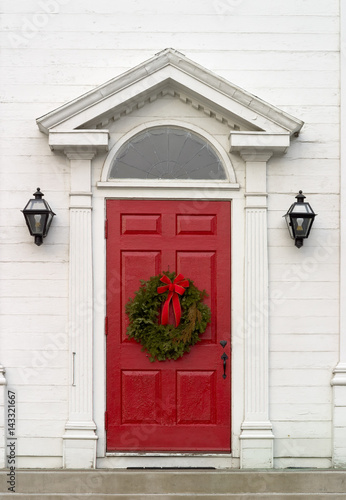 single Christmas wreath on red door of white church