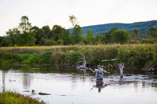 Senior flyfishing in a river at sunset