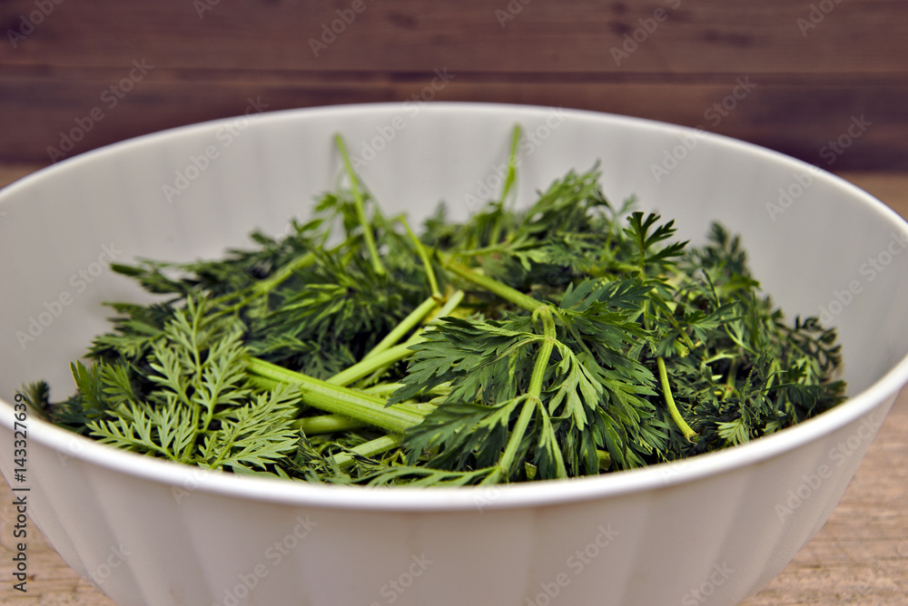 Bio waste-carrot tops in a white plastic bowl Bio waste-carrot tops in a white plastic bowl