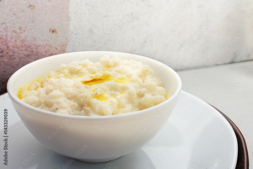 Porridge with milk and butter in a white plate with a blue frame for breakfast. Porridge with milk and butter in a white plate with a blue frame for breakfast.