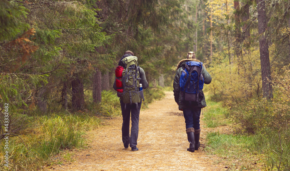 Two handsome, bearded men with backpacks hiking in autumn forest. Camp, adventure, traveling and trip concept.