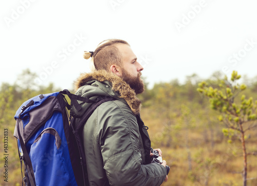Handsome, bearded guy hiking in swamps and taking pictures of autumn forest. Camp, adventure, trip, concept.