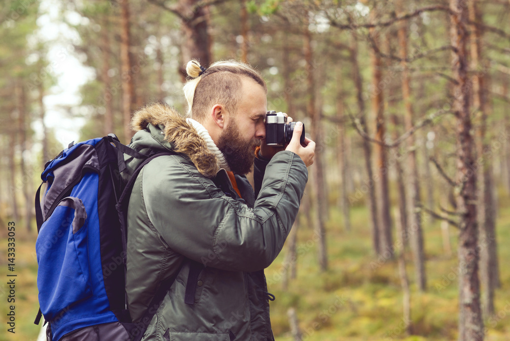 Bearded man hiking in swamps and taking pictures of autumn forest. Camp, adventure, trip and fishing concept. Bearded man hiking in swamps and taking pictures of autumn forest. Camp, adventure, trip and fishing concept.