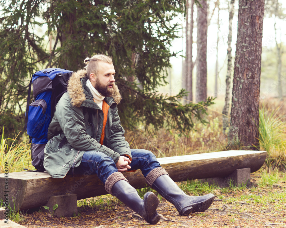 Brutal and handsome, bearded man sitting autumn in forest. Camp, adventure, trip and fishing concept. Brutal and handsome, bearded man sitting autumn in forest. Camp, adventure, trip and fishing concept.