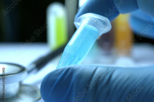 Fototapeta Naklejka Na Ścianę i Meble -  Gloved Hand Holding Research Vial, Stem Cell Research Substance in Vial
