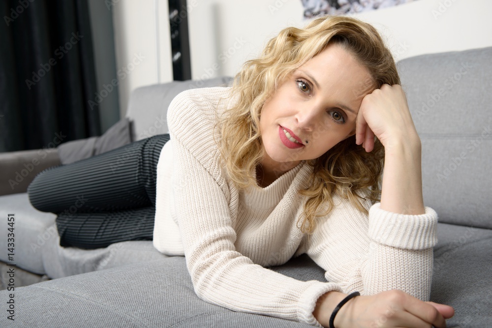 attractive blond woman relaxing on the sofa in her home attractive blond woman relaxing on the sofa in her home