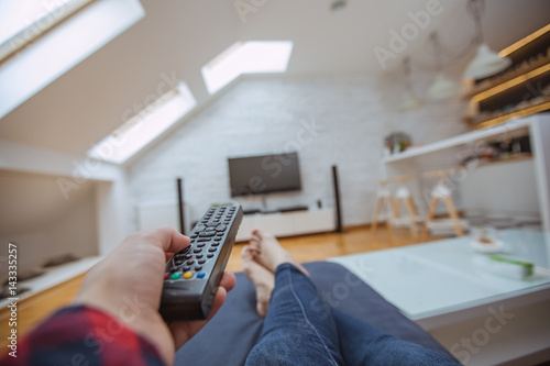Close up and part of human hand using remote control on sofa
