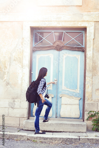 Young traveler girl  staying near an old door. Vacation  summer  holiday  journey  concept.
