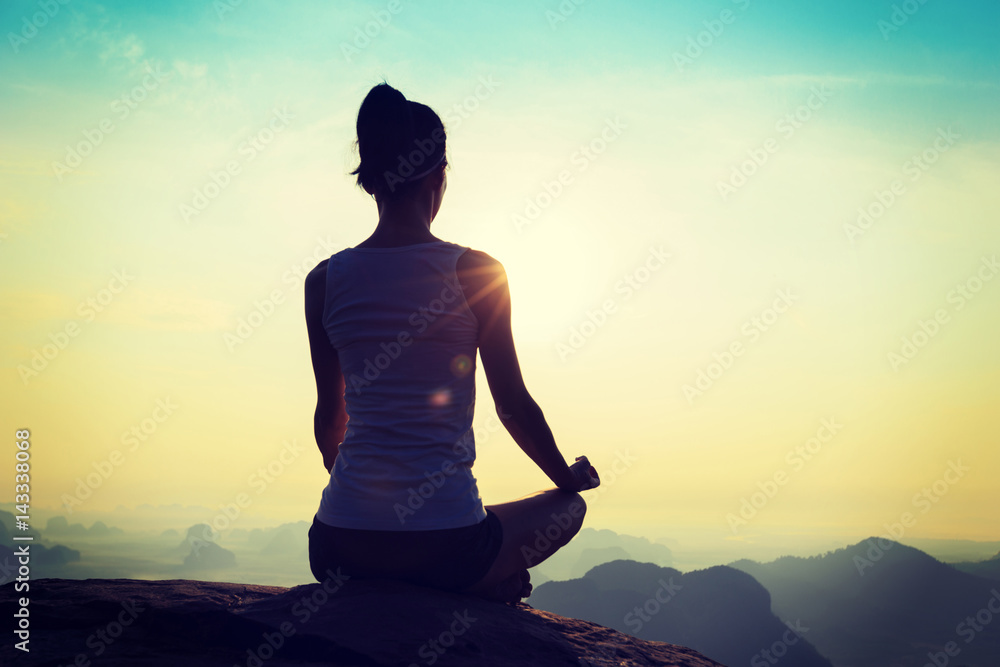 young fitness yoga woman meditating on sunrise mountain peak