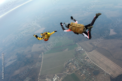 Skydivers with old-school equipment are in the sky.