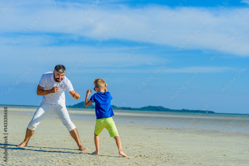Happy father and son at the tropical beach, laughing and enjoing time together Happy father and son at the tropical beach, laughing and enjoing time together