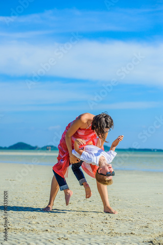 Dancing with mom. Happy family - mom and son - at the tropical beach, laughing and enjoing time together.