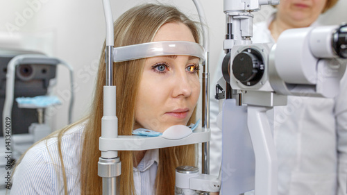Attentive optometrist examining female patient on slit lamp in ophthalmology clinic