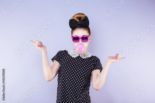 Portrait humoristique d'une jeune femme faisant une bulle de chewing gum les mains sur les cotés photo