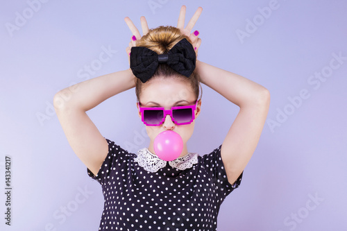 фотографія Portrait humoristique d'une jeune femme faisant une bulle de chewing gum les doi