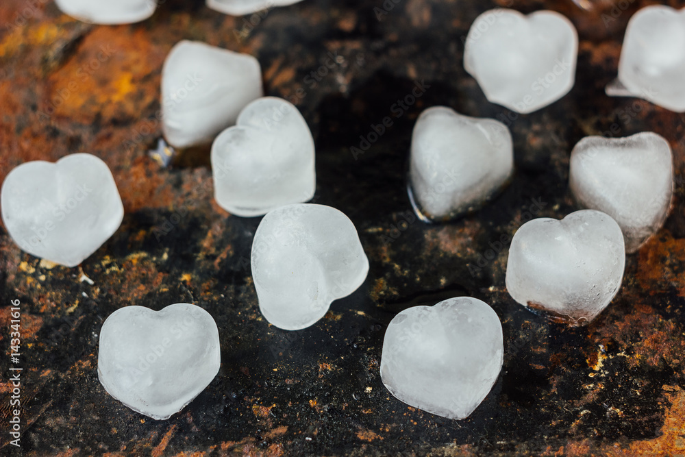 Obraz premium ice in form of hearts on black rustic surface.
