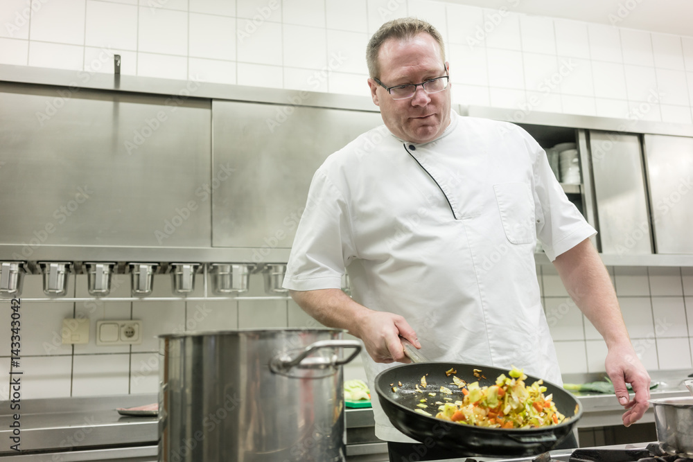Chef in restaurant frying vegetables in pan Chef in restaurant frying vegetables in pan