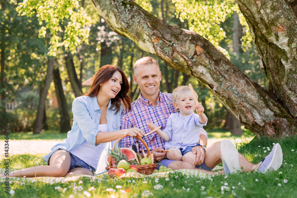 Fototapeta premium Happy family spending time in the park with son holding the pretzel.