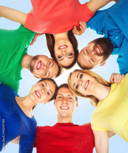 Group of happy students standing together and looking at camera over blue background. School, university, education, concept.