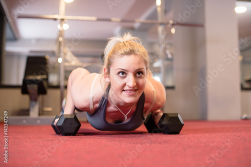 Athlete Woman Doing Push-ups and Lifting Weights in Gym close up