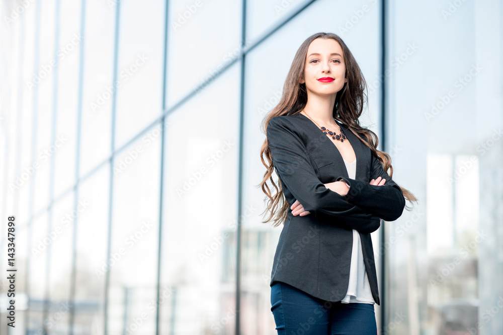 Portrait of a young caucasian businesswoman standing outdoors near the modern facade Portrait of a young caucasian businesswoman standing outdoors near the modern facade