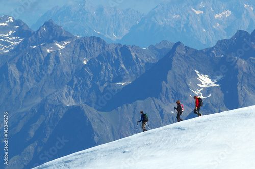 Group of walking Tourists on the glacier with mountains on background