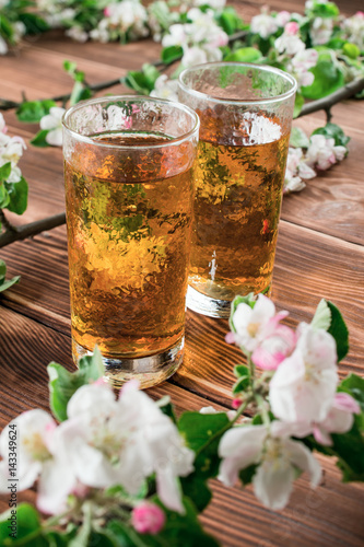 Apple juice in a glass with apple flowers on the table