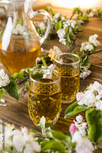 Apple juice in a glass with apple flowers on the table