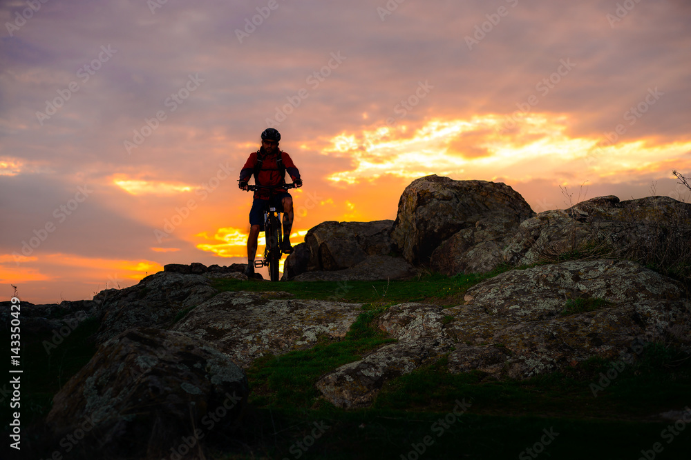 Silhouette of Cyclist with Mountain Bike on the Spring Rocky Trail at Beautiful Sunset. Extreme Sports and Adventure Concept.