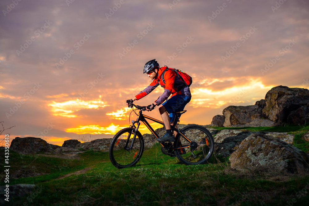 Fototapeta premium Cyclist Riding Mountain Bike on the Spring Rocky Trail at Beautiful Sunset. Extreme Sports and Adventure Concept.