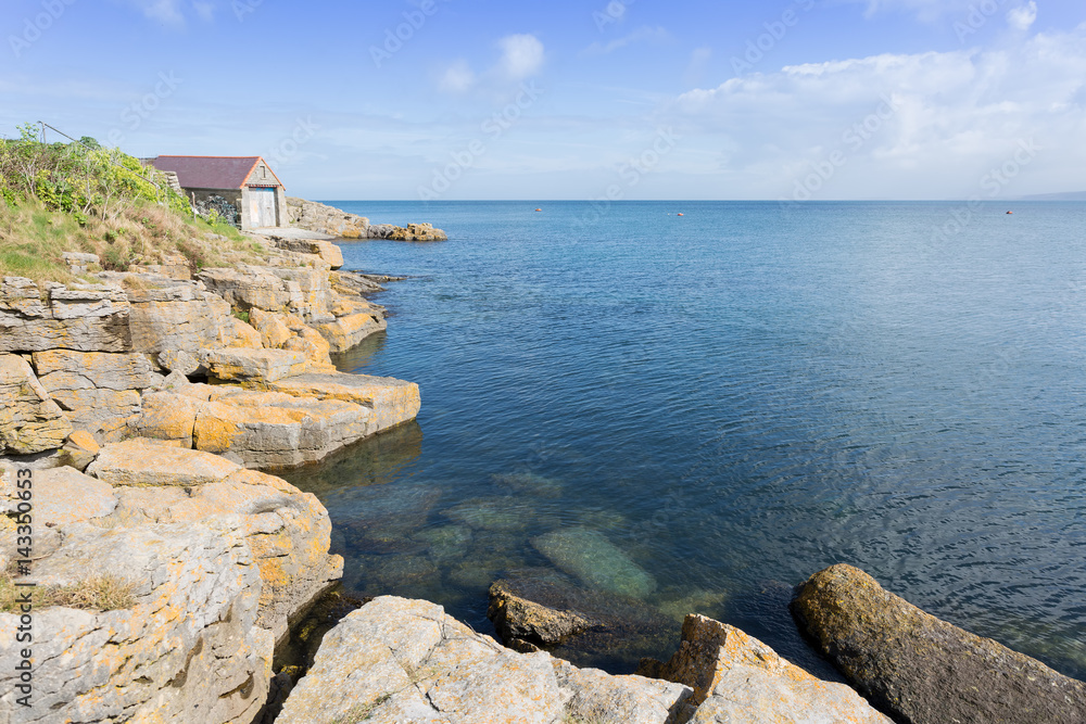 Rocky coastline at Moelfre with old lifeboat station, Anglesey North Wales