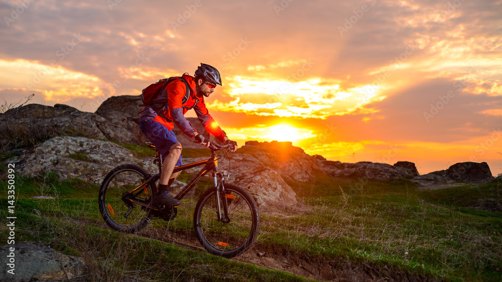 Cyclist Riding Mountain Bike on the Spring Rocky Trail at Beautiful Sunset. Extreme Sports and Adventure Concept. Cyclist Riding Mountain Bike on the Spring Rocky Trail at Beautiful Sunset. Extreme Sports and Adventure Concept.