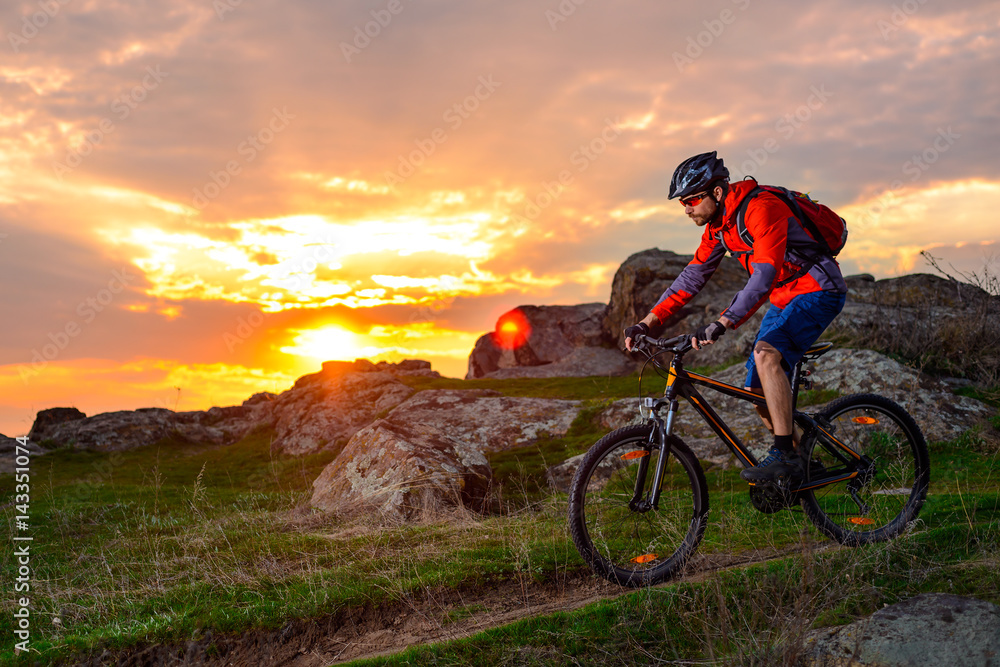 Fototapeta premium Cyclist Riding Mountain Bike on the Spring Rocky Trail at Beautiful Sunset. Extreme Sports and Adventure Concept.
