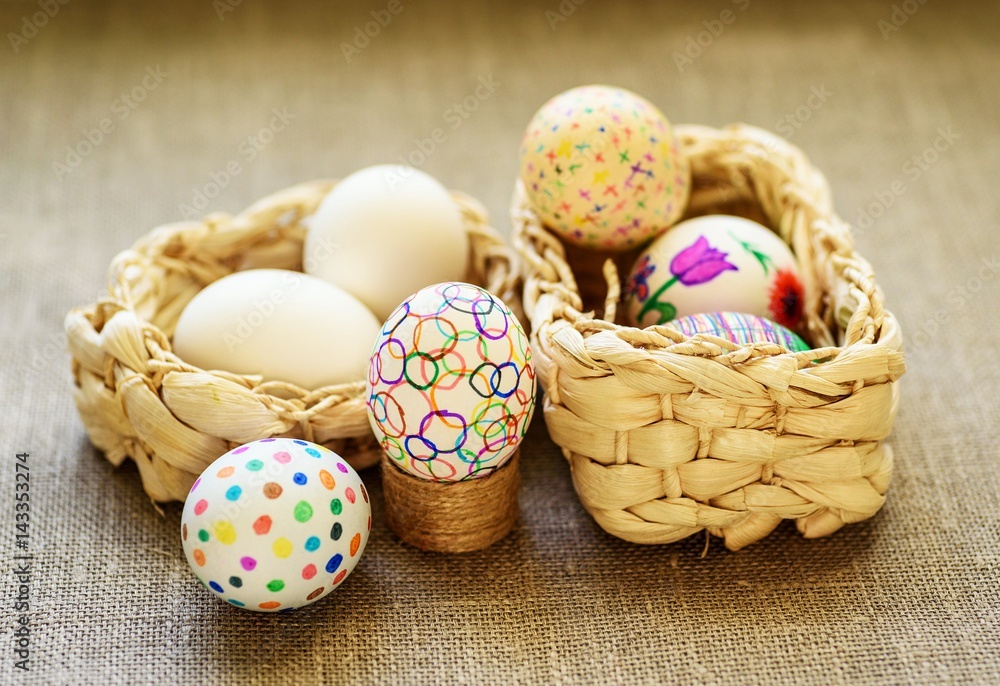 Easter eggs in a two wicker basket on the tablecloth of burlap Easter eggs in a two wicker basket on the tablecloth of burlap