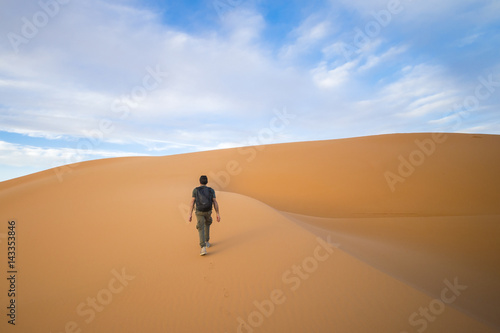A man walks on the dunes in the Sahara Desert at sunset - Merzouga - Morocco