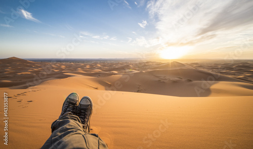 A man is enjoying the sunset on the dunes in the Sahara Desert - Merzouga - Morocco