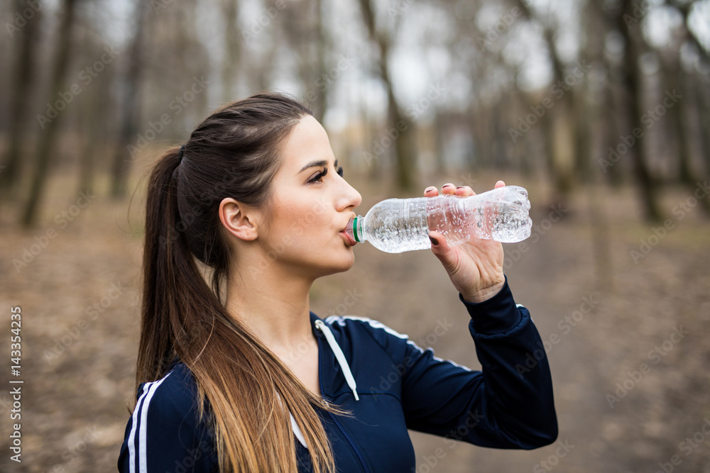 Young woman drinking water after jogging in park outdoors. Young woman drinking water after jogging in park outdoors.
