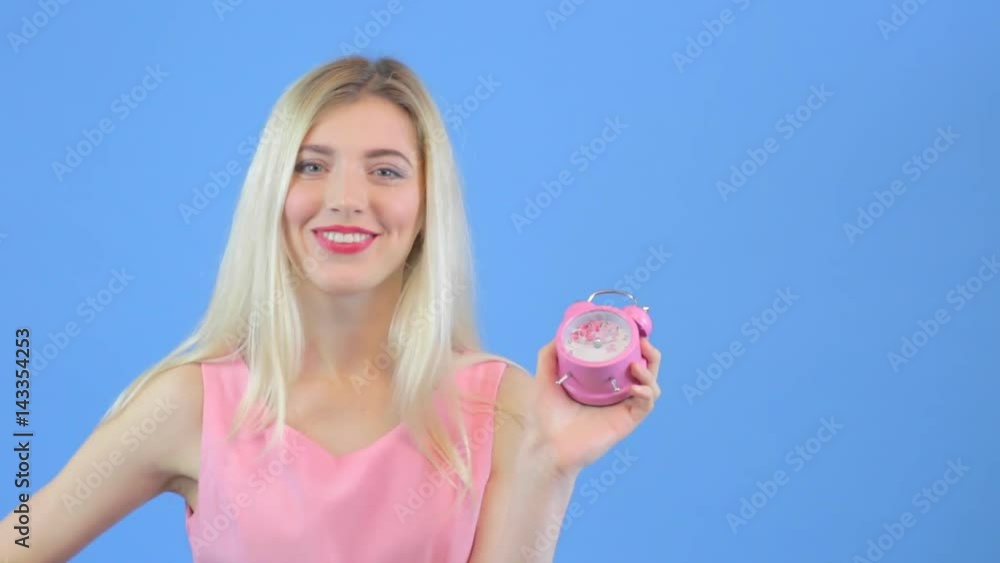 Attractive yong woman yawning, Holds an alarm clock in hand