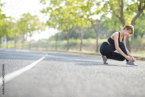 Asian young woman runner tying shoelaces healthy lifestyle jogging © jaengpeng