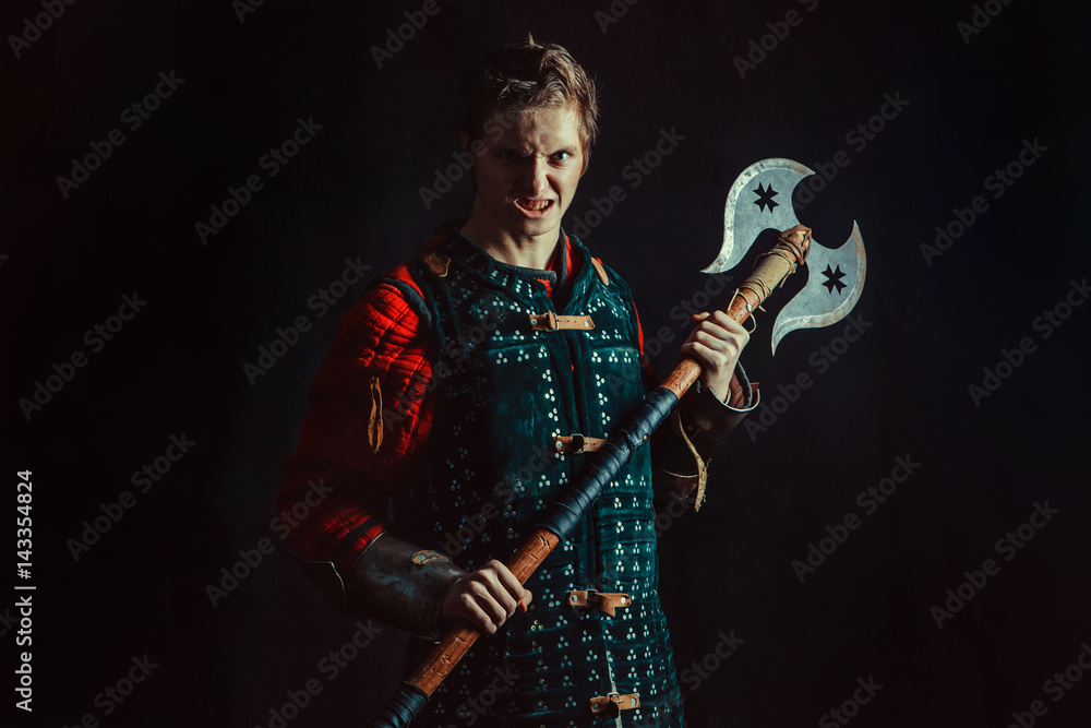 Obraz premium Young medieval warrior with the axe. Dark background.