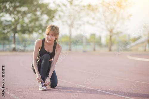 Asian young woman runner tying shoelaces healthy lifestyle jogging