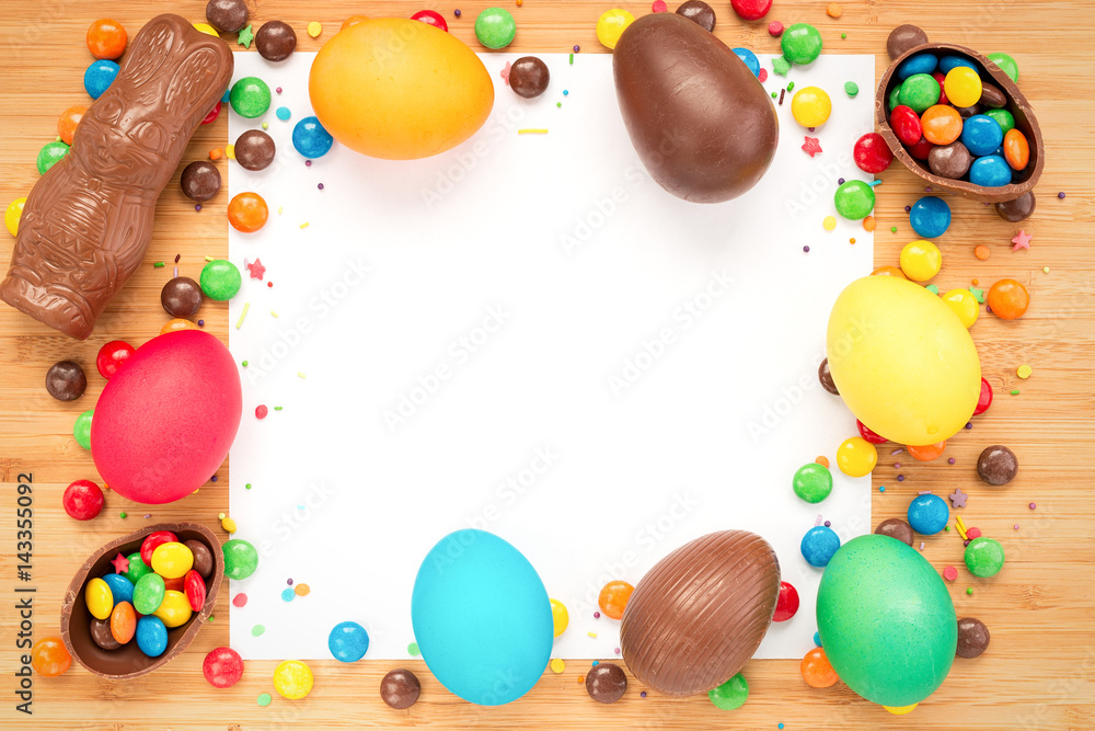 Multicolored easter eggs, chocolate eggs and easter bunnies, colorful candy cane on a textured wooden background. The concept of a holiday and a happy Easter. With space for text