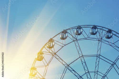 Ferris wheel against a blue sky with the sun