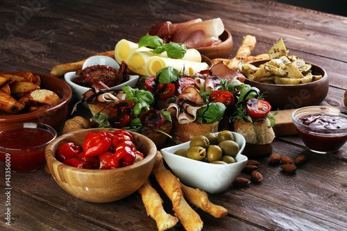 Italian antipasti wine snacks set. Cheese variety, Mediterranean olives, pickles, Prosciutto di Parma, tomatoes, artichokes and wine in glasses