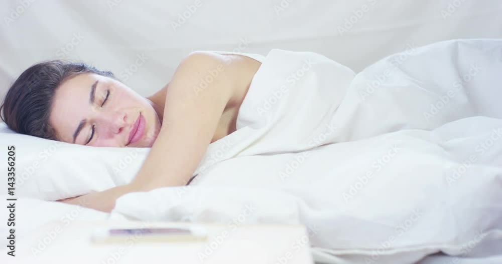 A simple working day for a beautiful young girl sleeping in a warm bed, covered with a soft warm white blanket, on a white background. A simple working day for a beautiful young girl sleeping in a warm bed, covered with a soft warm white blanket, on a white background.