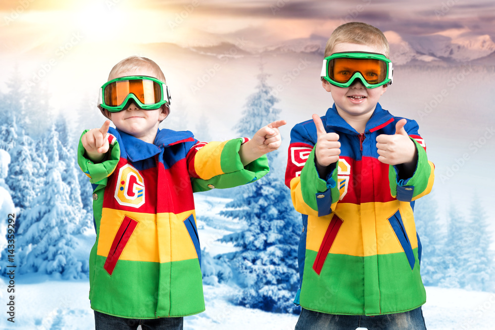 Two brothers of the boy snowboarder in bright ski jackets and goggles is skiing in the mountains. Two brothers of the boy snowboarder in bright ski jackets and goggles is skiing in the mountains.